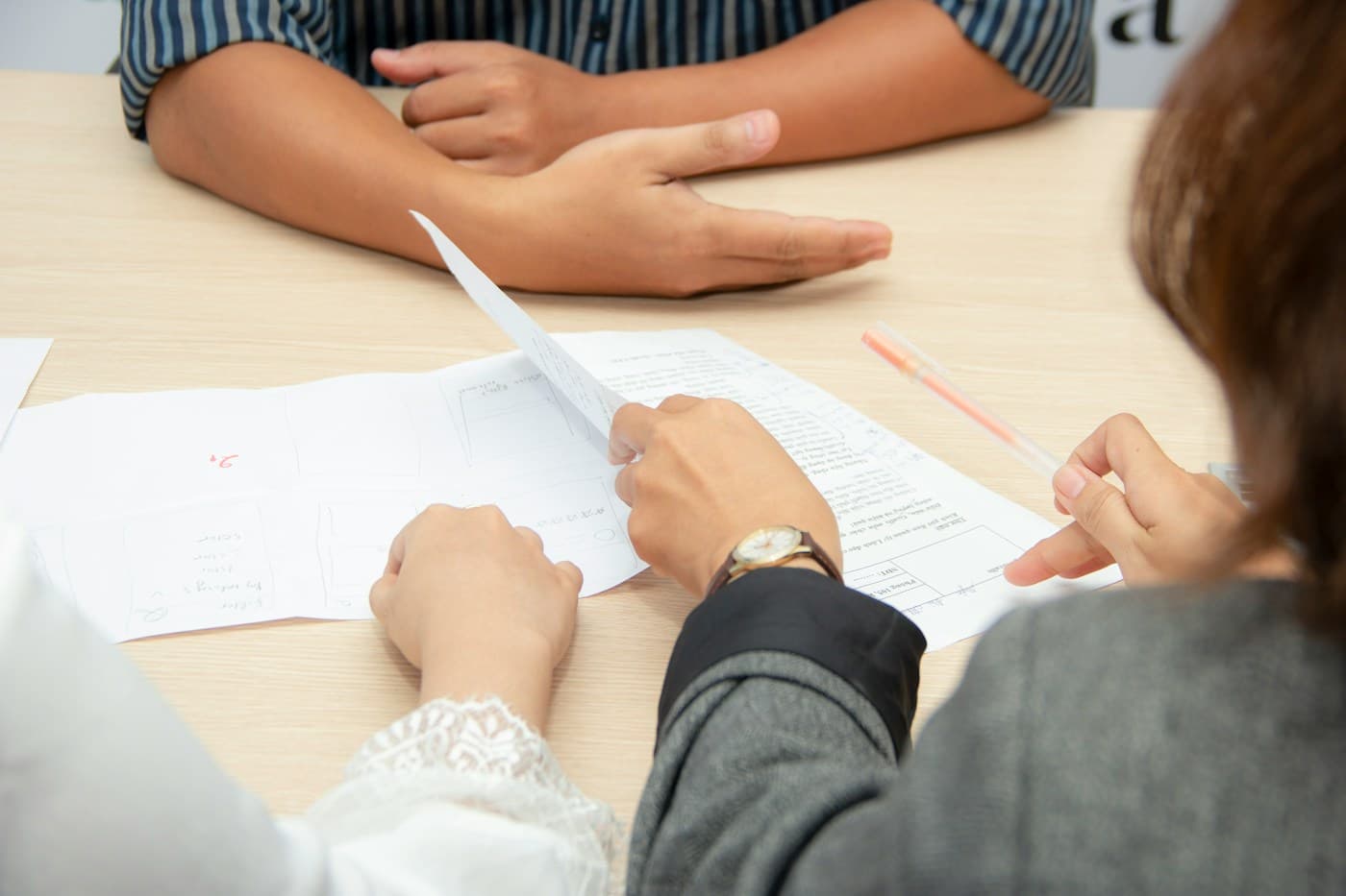 Two people going over a printed CV at a table, one pointing at a line with a pen